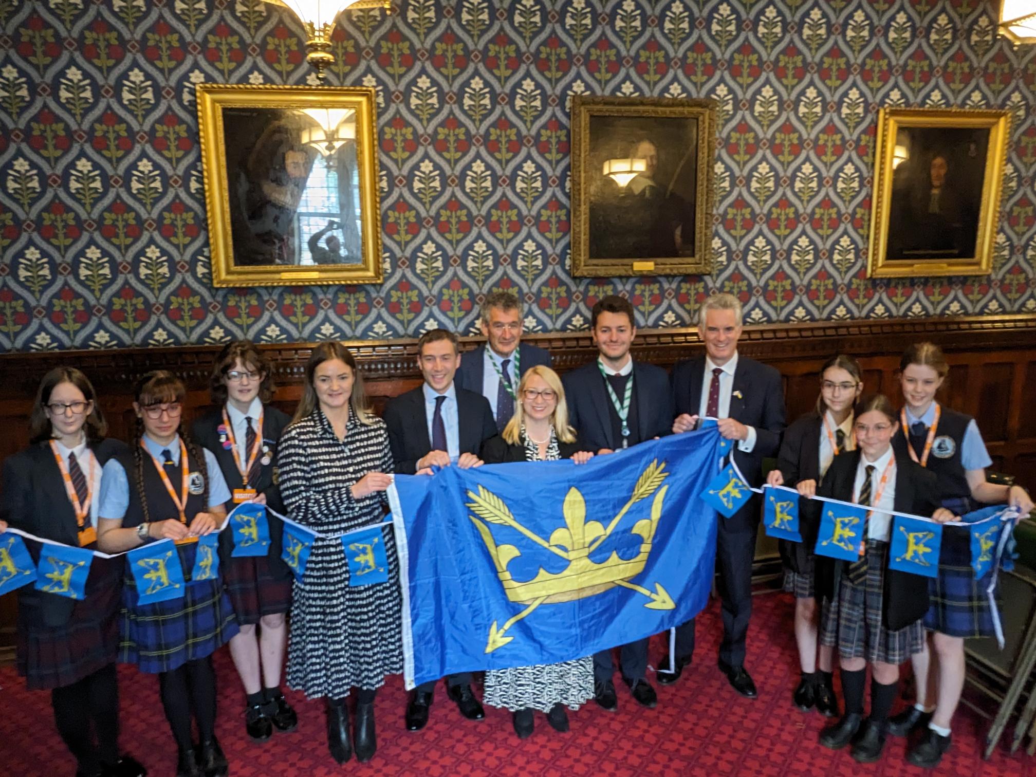 School pupils and MPs from Suffolk with the Suffolk Day flag (a gold crown and arrows on a blue background) and bunting