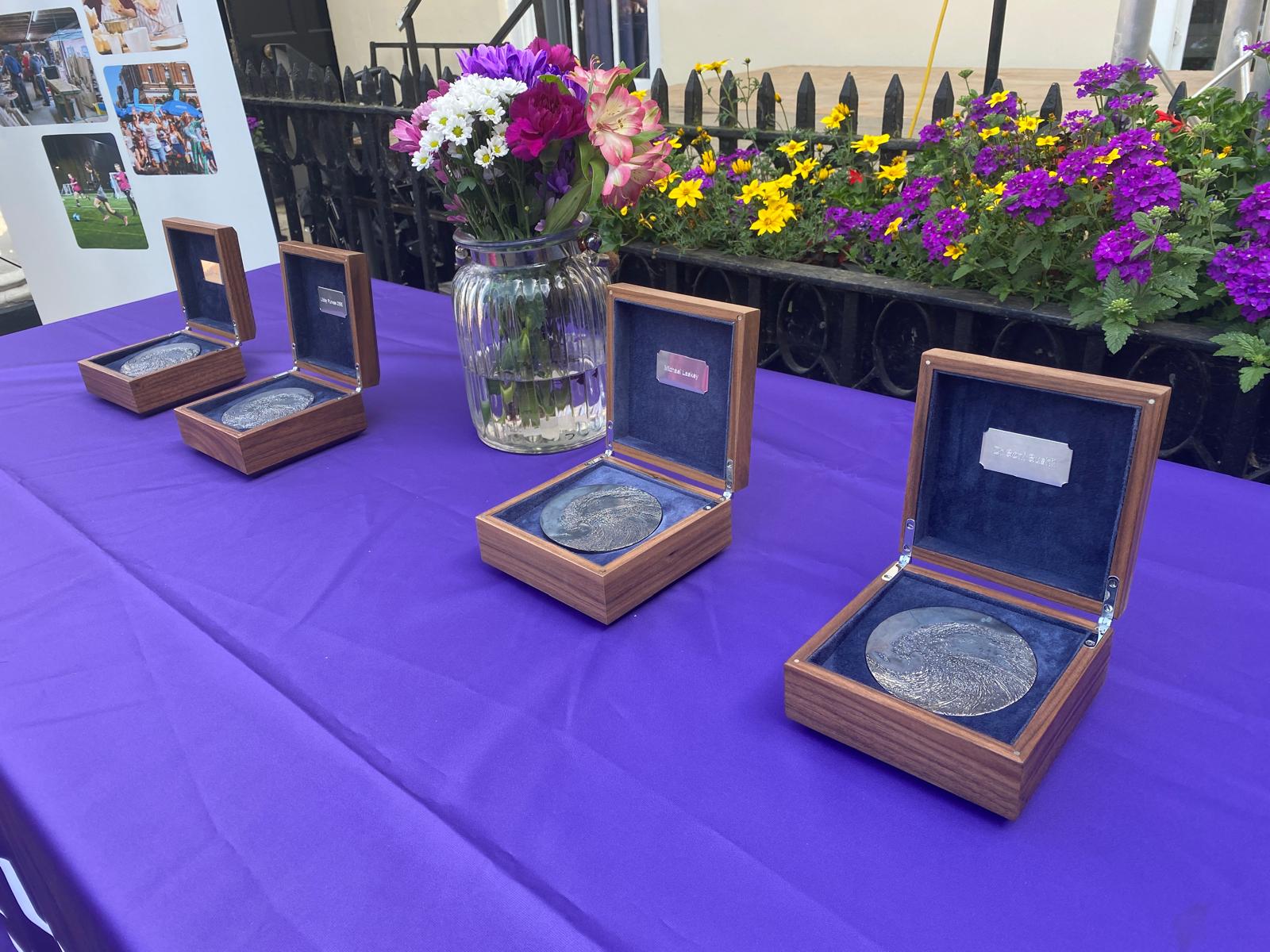 Four boxes with Suffolk Medal sit on a purple table cloth